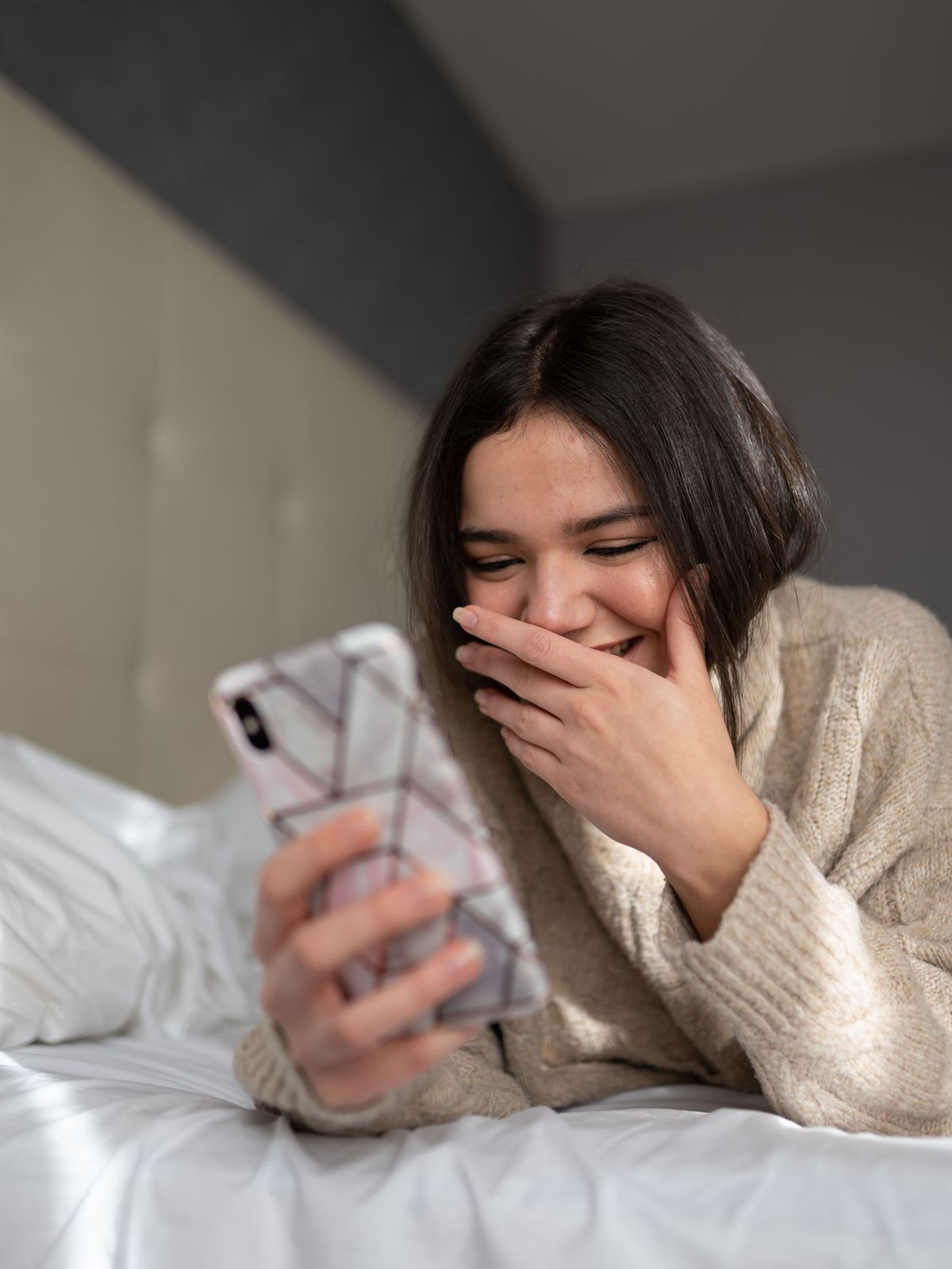A patient laughing as she reads a reply from her clinic on her phone in the evening