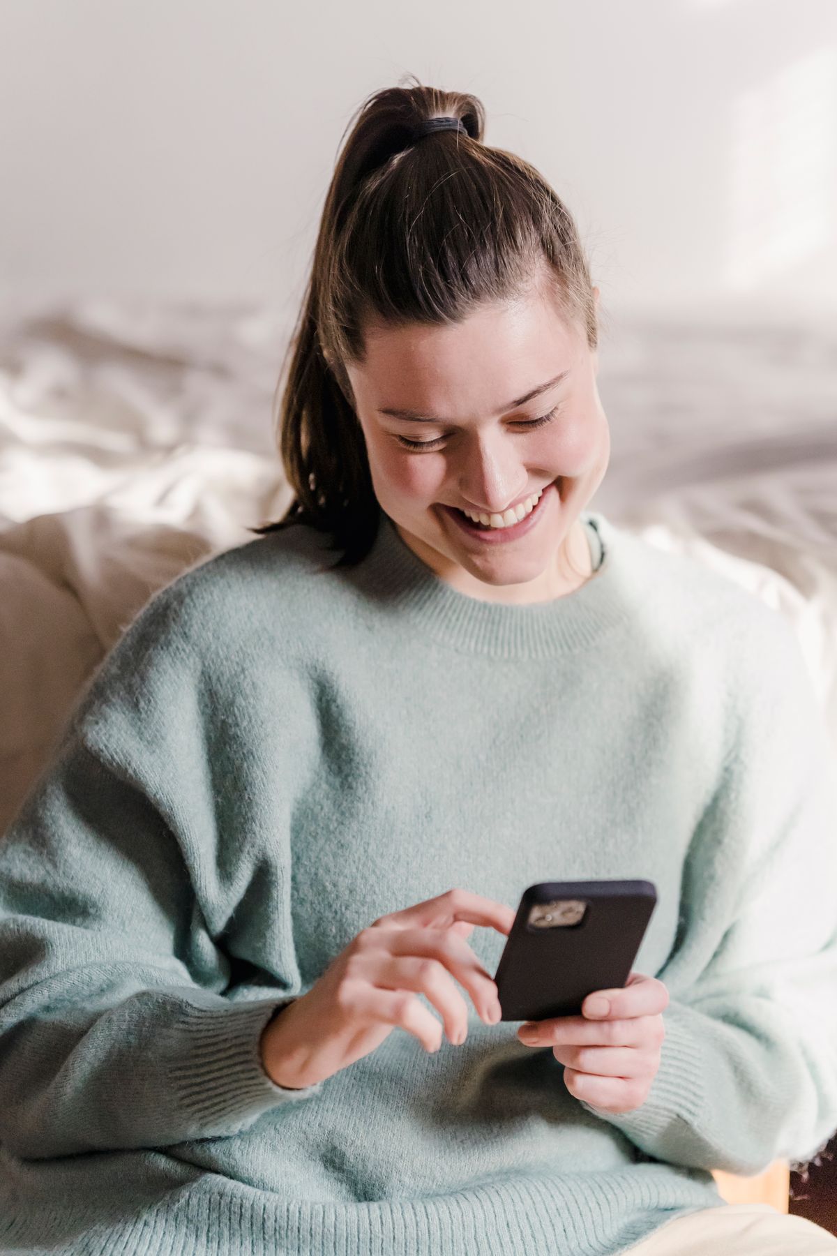 A patient smiling as she fills out a form on her phone
